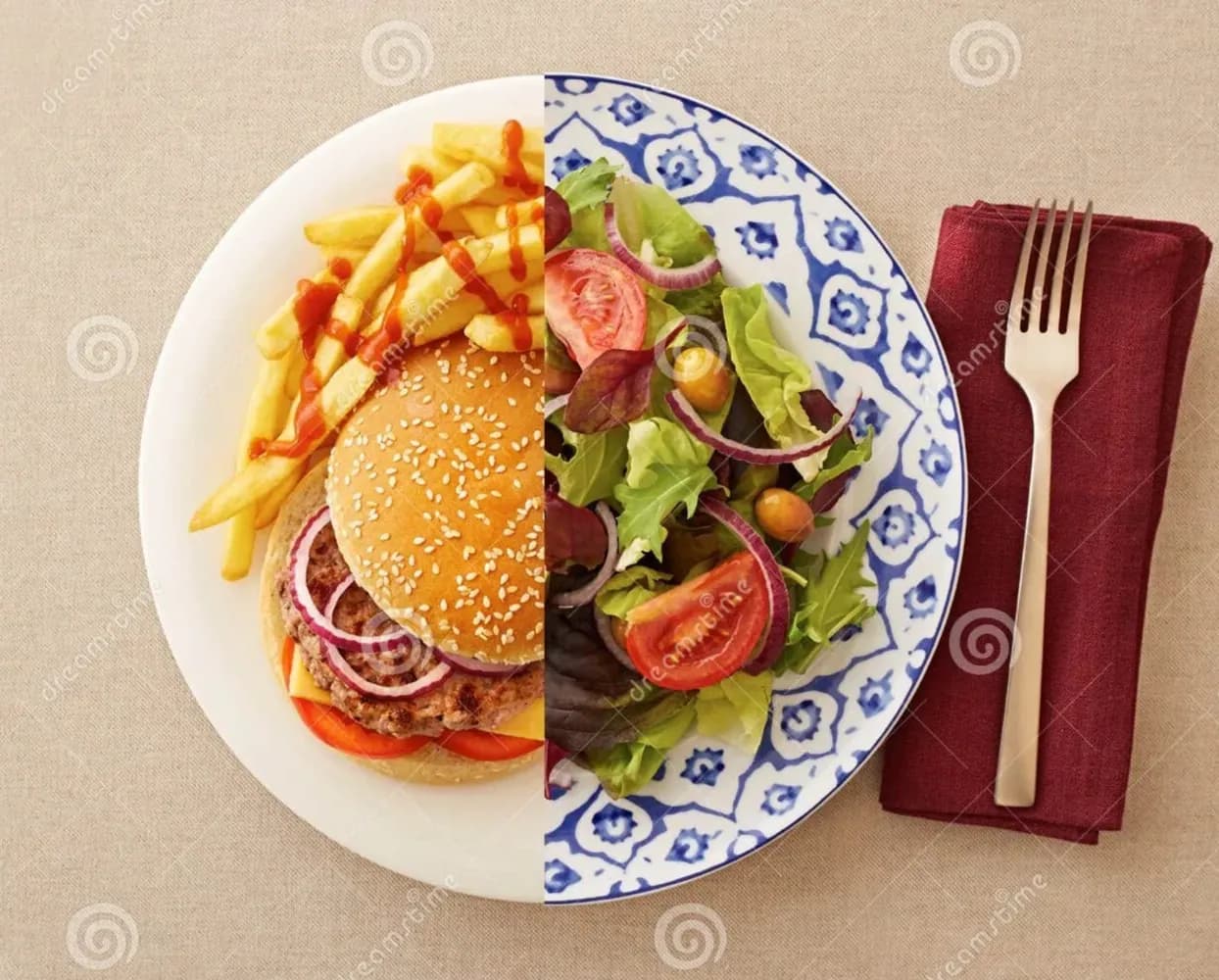 Talerz widziany z góry, przecięty na pół. Po lewej burger z frytkami i ketchupem, po prawej sałatka z pomidorem i czerwoną cebulą. Obok widelec na bordowej serwetce.